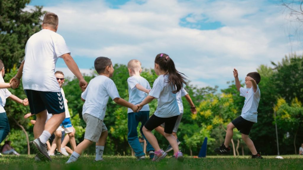 Group of children having fun and playing games together in a sunny park.